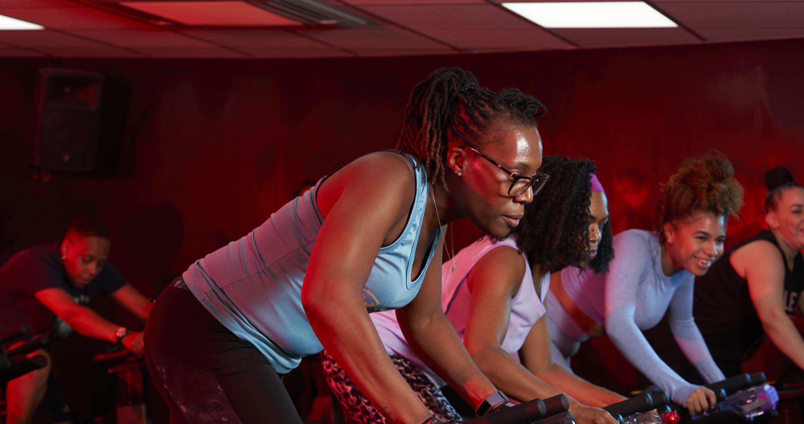 A black woman taking part in a spin cycling class