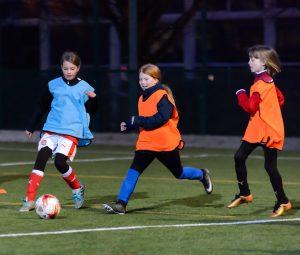 A group of young girls playing football at a local club