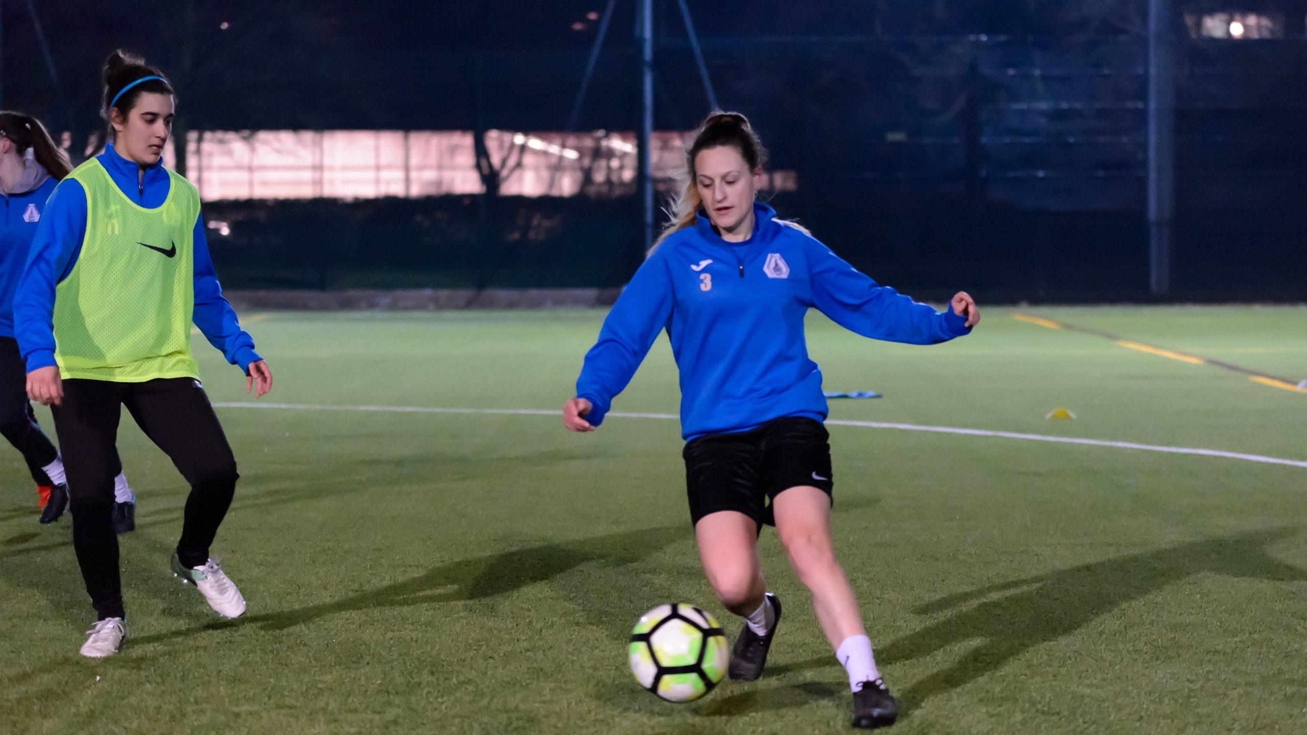 A white woman aged 20-25 kicking a football