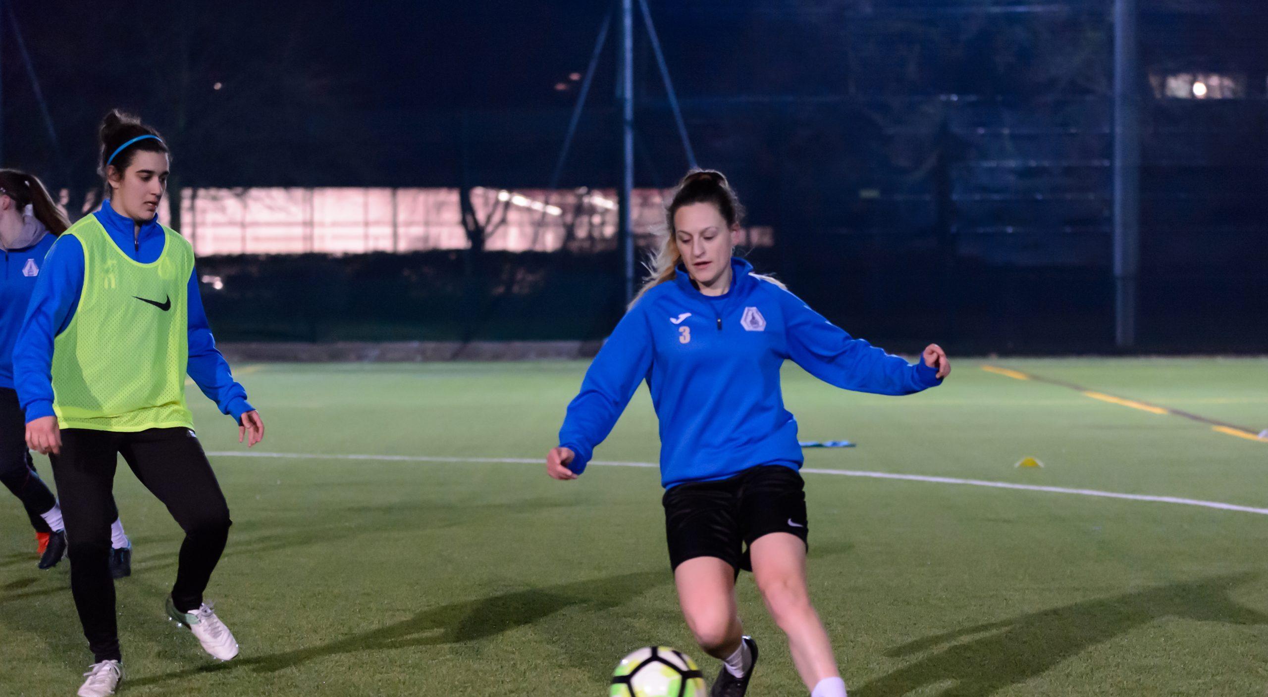 A white woman aged 20-25 kicking a football