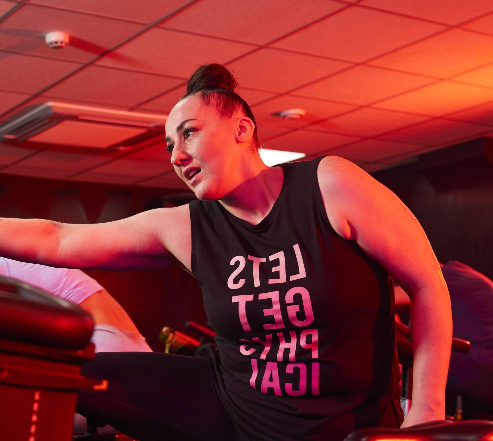 White woman aged 30-40 stretching in a gym class