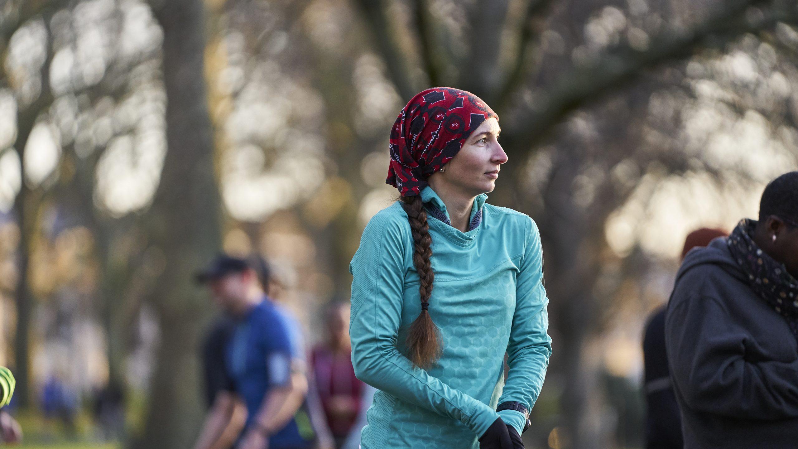 White woman with long brown hair aged 30-40 shivering before starting a running race