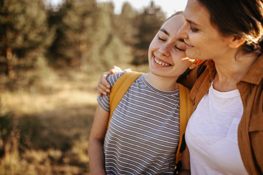 Loving mother and daughter embracing on hiking tour