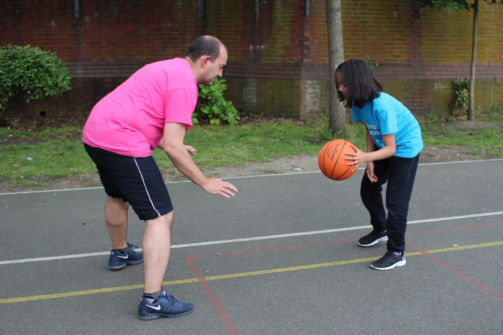 daughter bouncing a basketball facing her dad