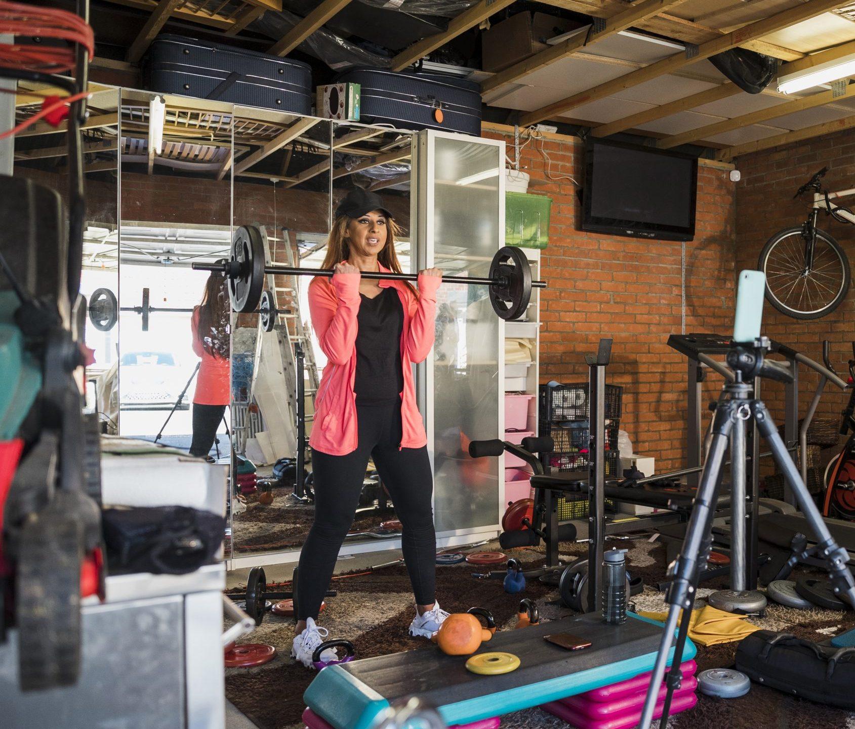 South Asian woman aged 45-55 weightlifting in her garage