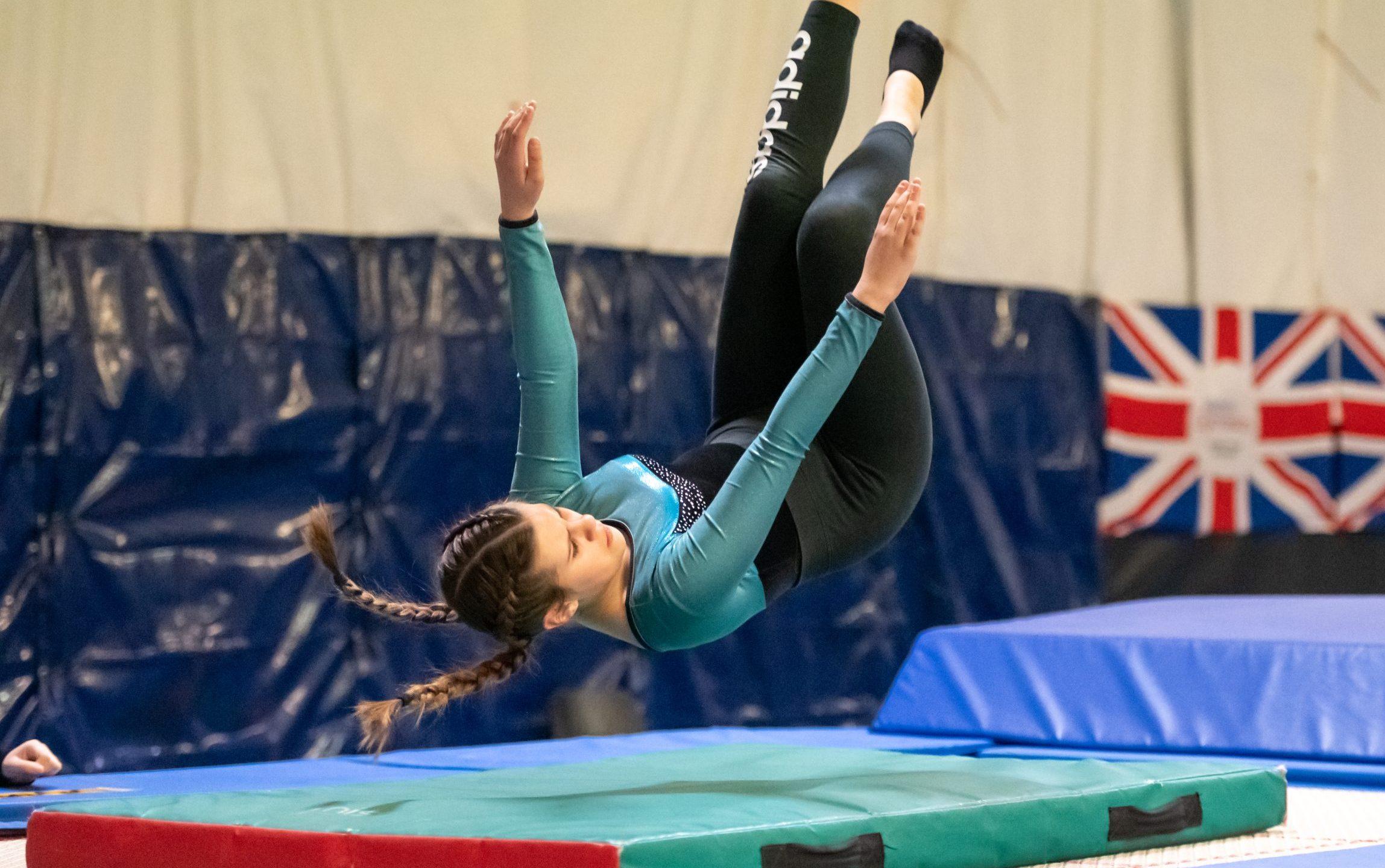 White teenage girl performing a gymnastics tumble