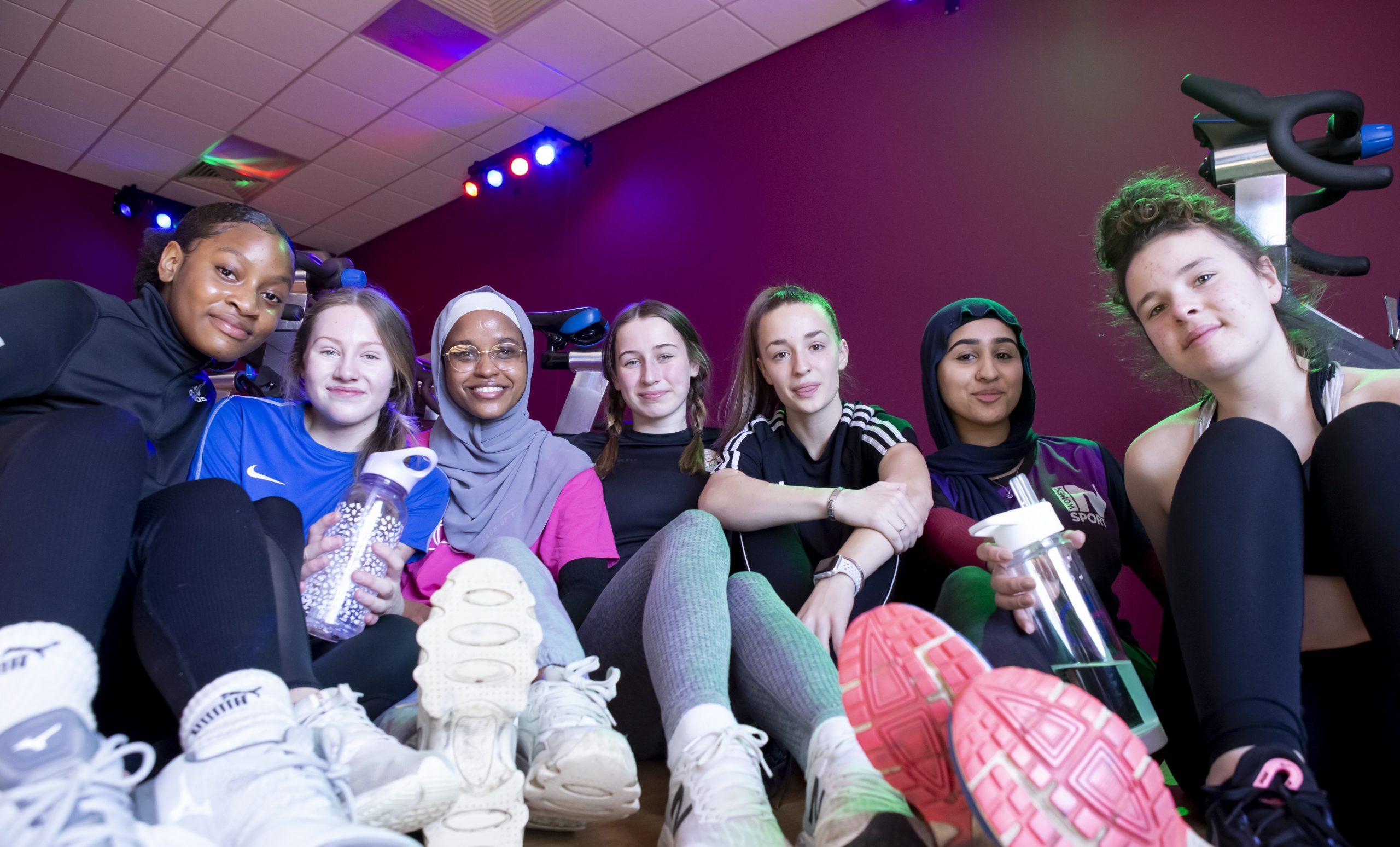 A group of girls sitting together in a leisure centre, smiling