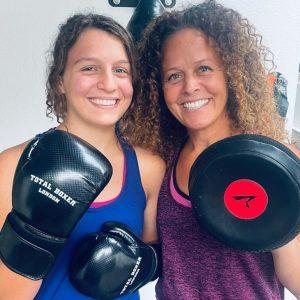 A mum and daughter posing with their boxing gloves on