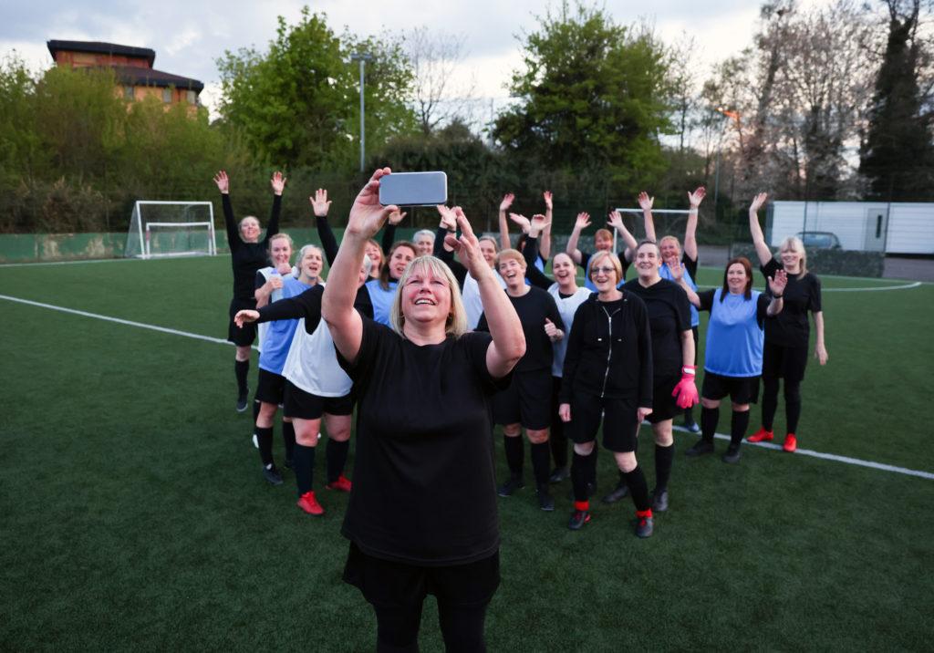 Carol taking a photo with her football team