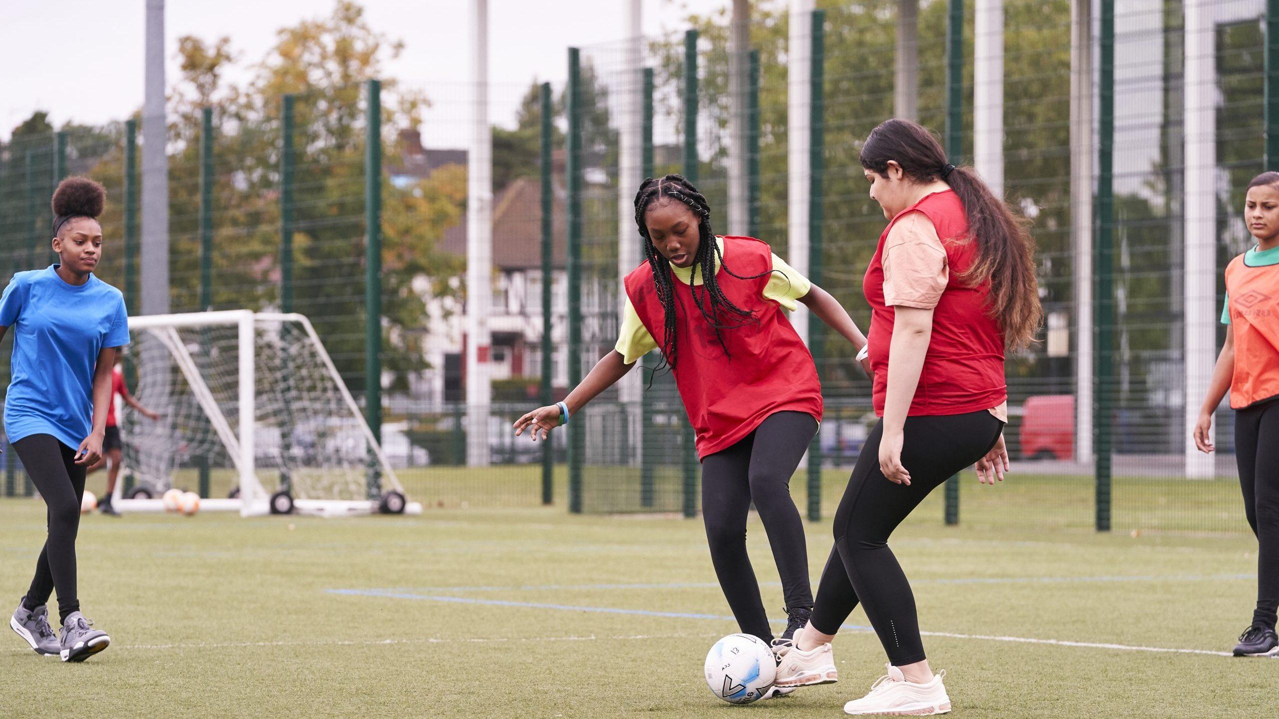 Two teenage girls playing football at school