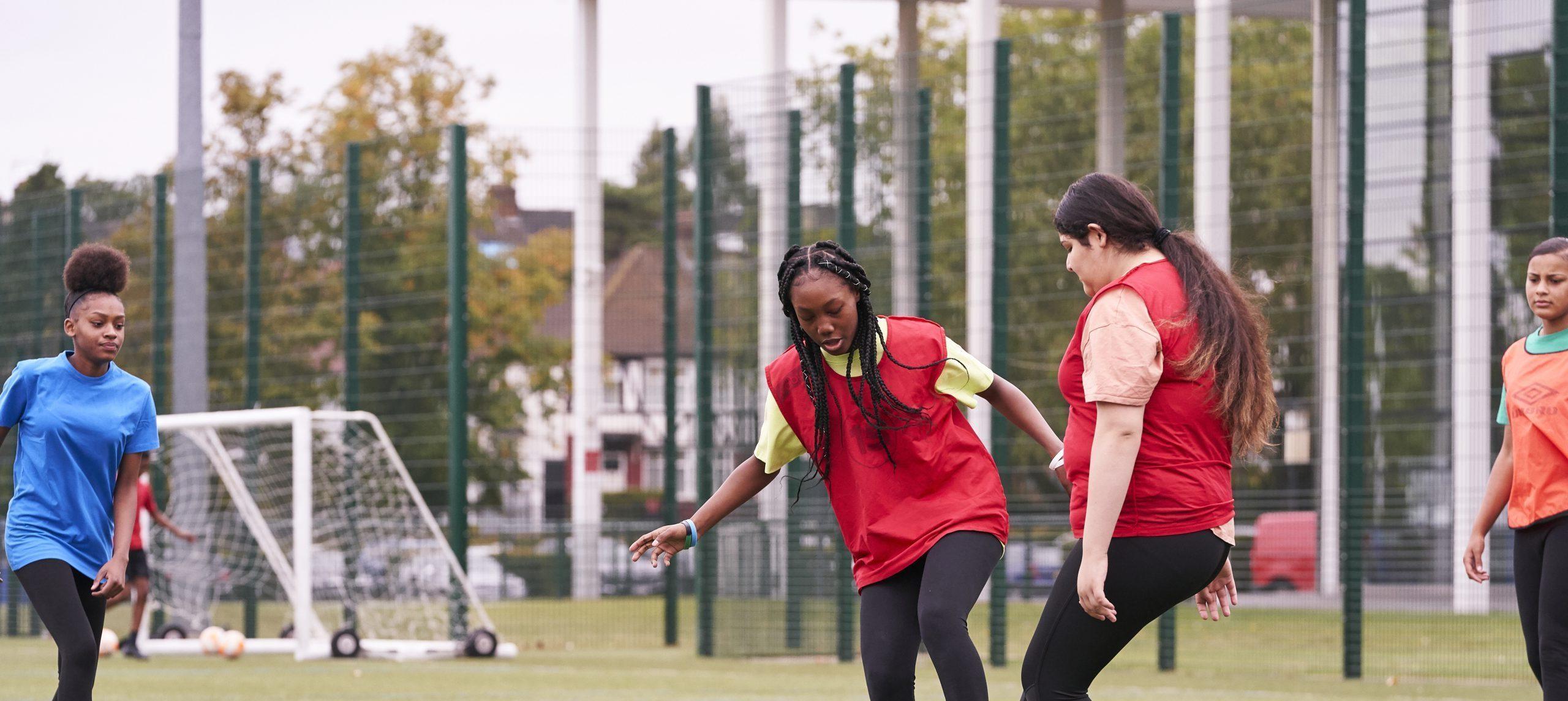 Two teenage girls playing football at school