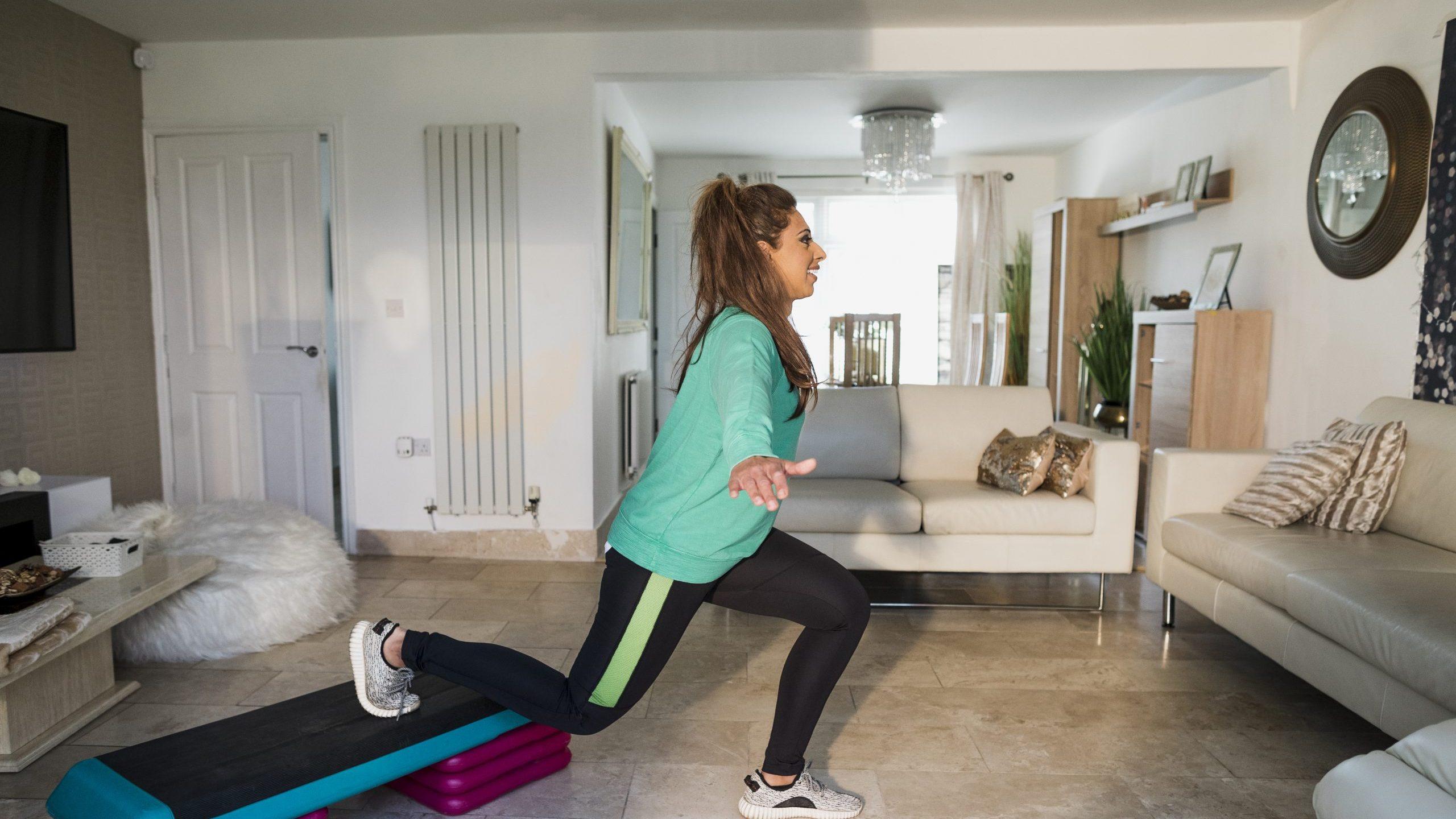 Shazia, a south asian woman aged 50-55 doing a step workout in her living room