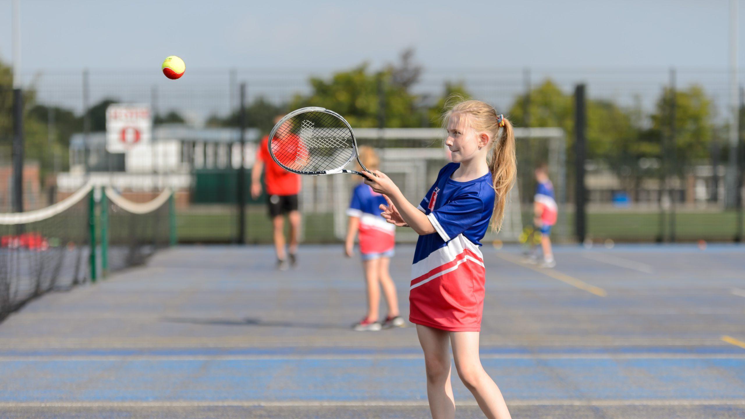 Young girl hitting a ball with a tennis racket