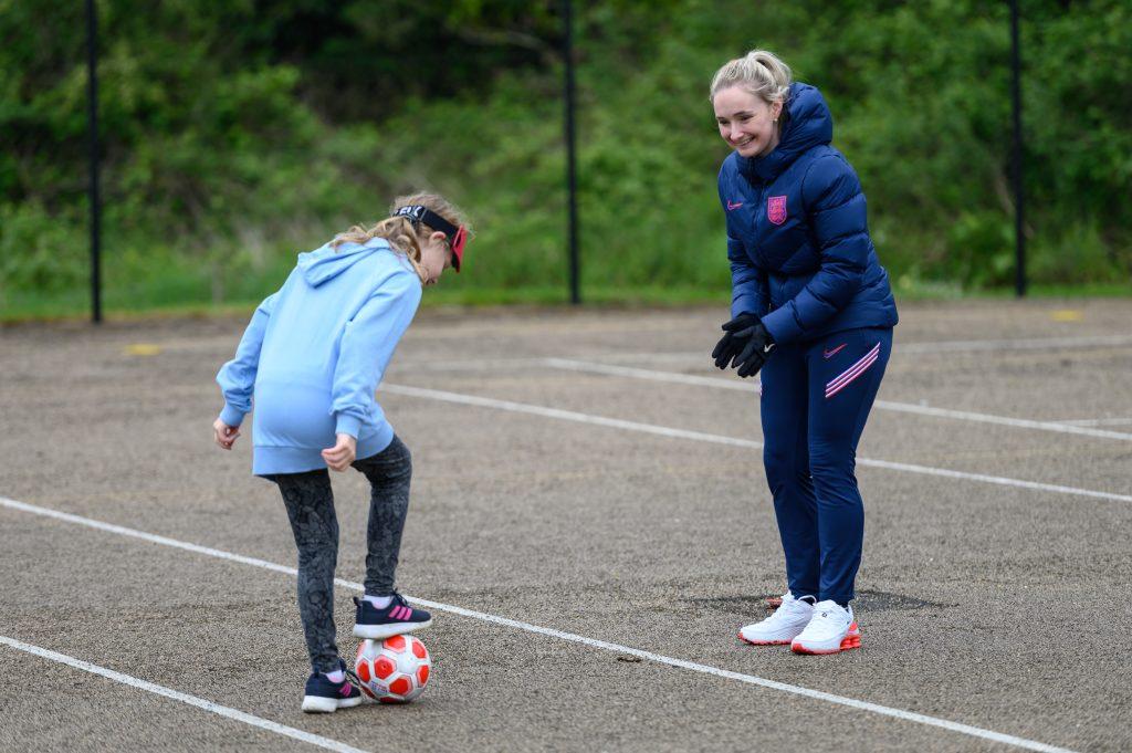 A young girl practicing football skills in the primary school playground