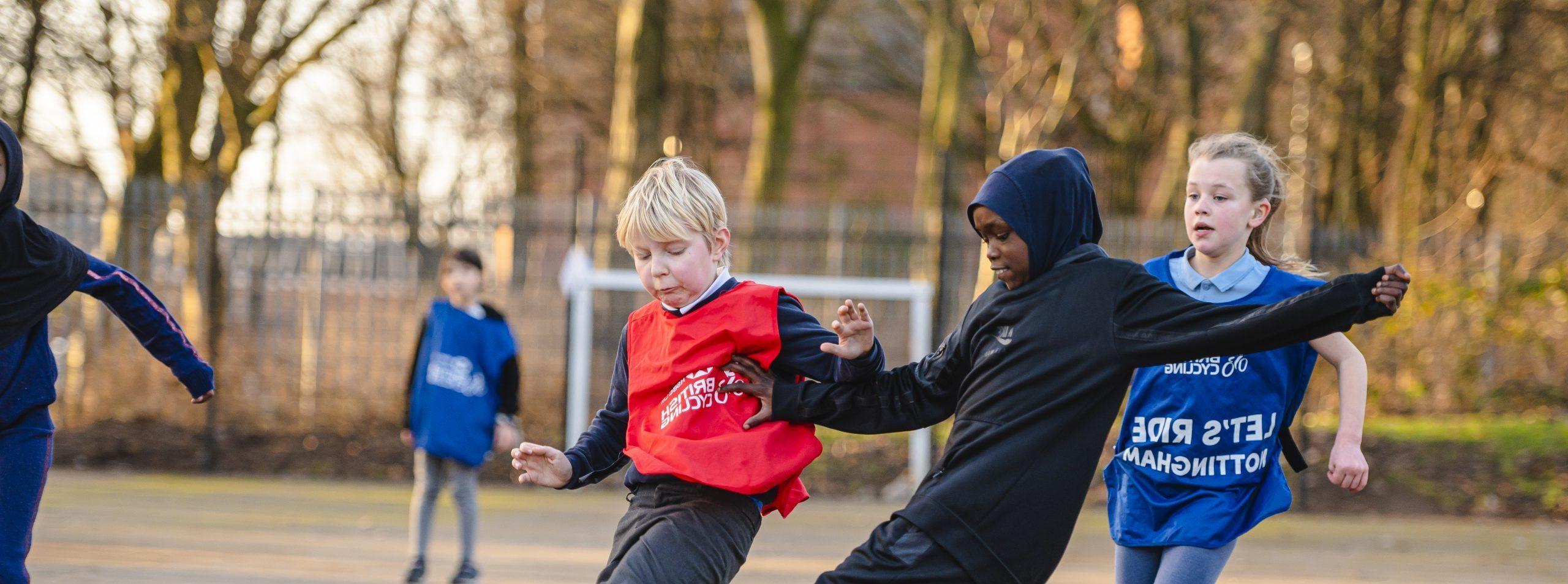 A young Muslim girl and young white boy playing football together at school