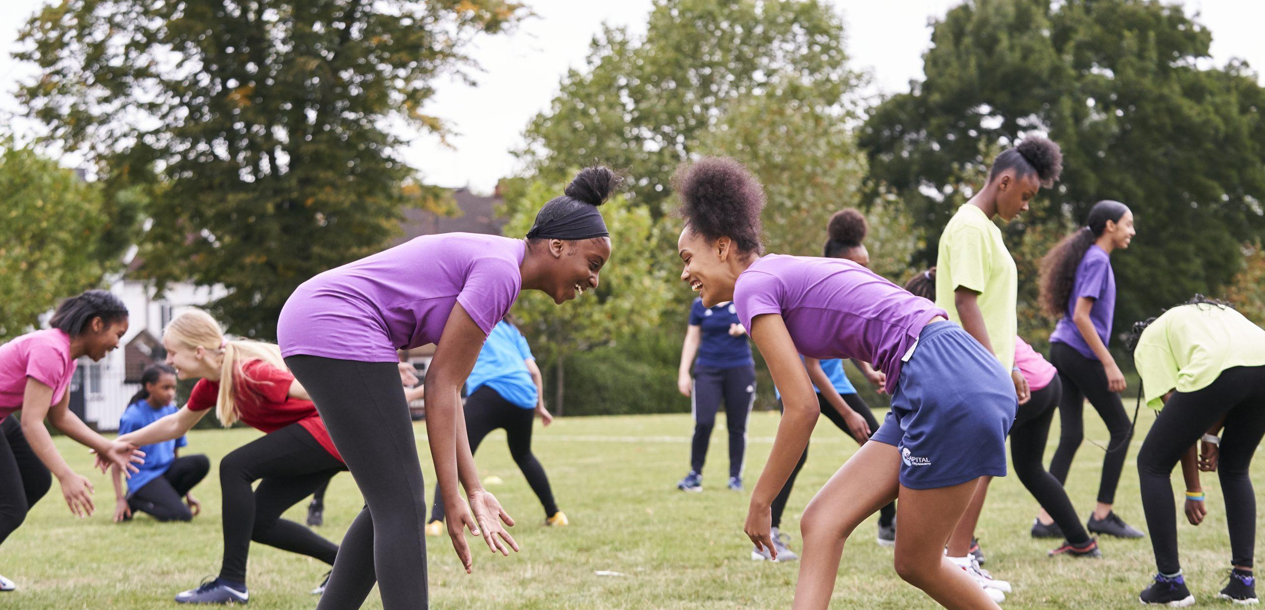 Two black teenage girls playing rugby at school