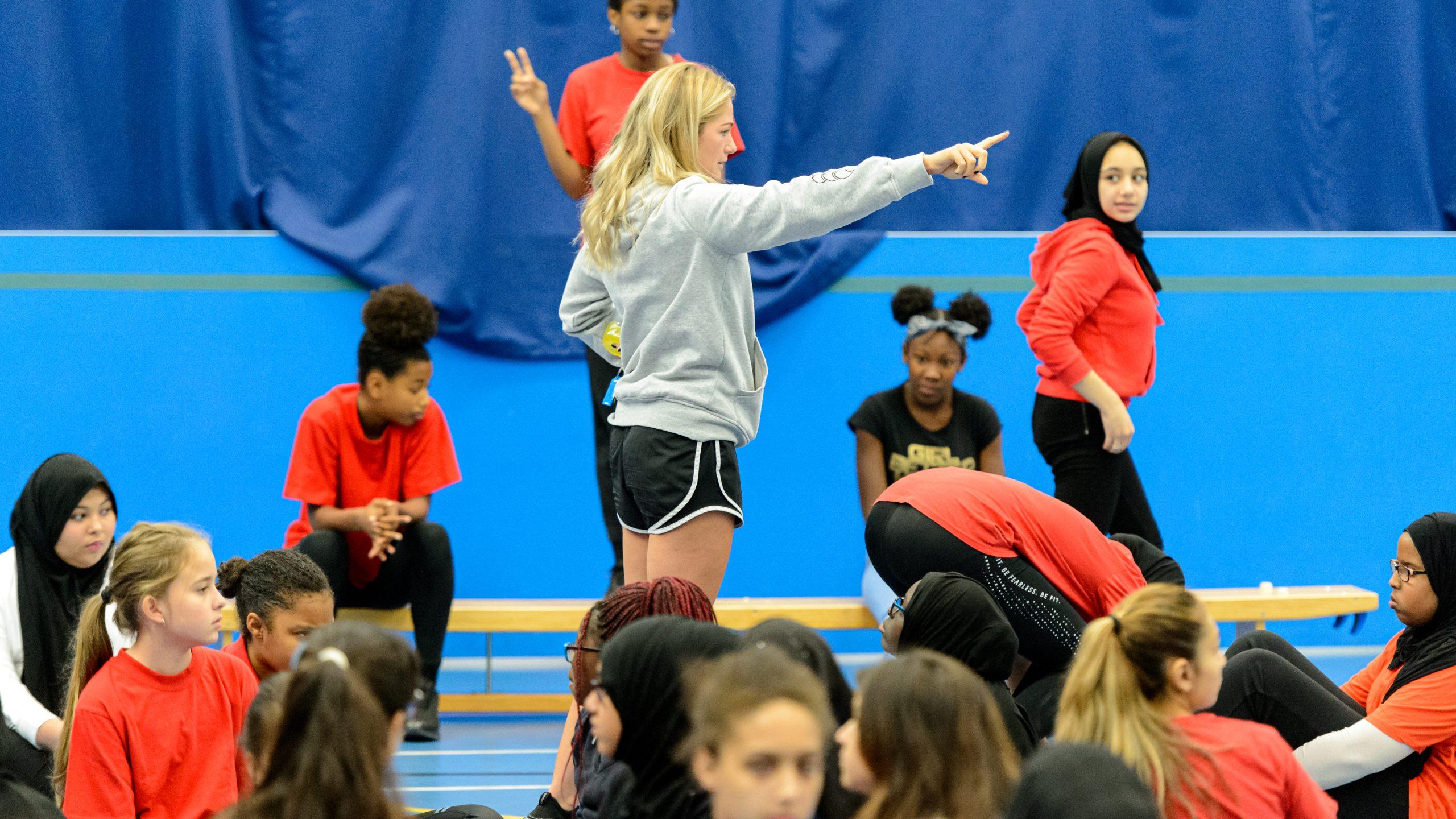 A young female coach leading young people in PE