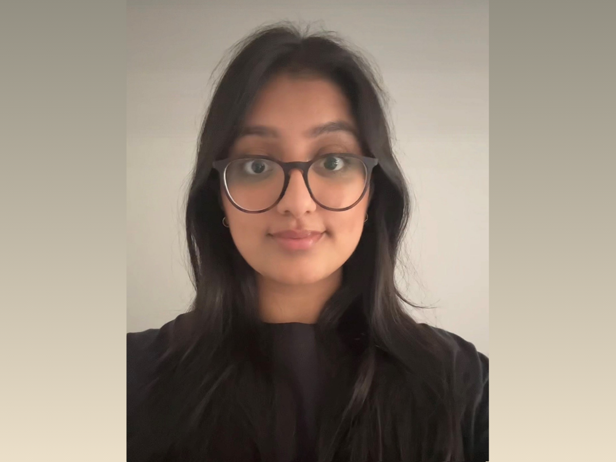 Anisha, a young south asian woman wearing glasses and smiling