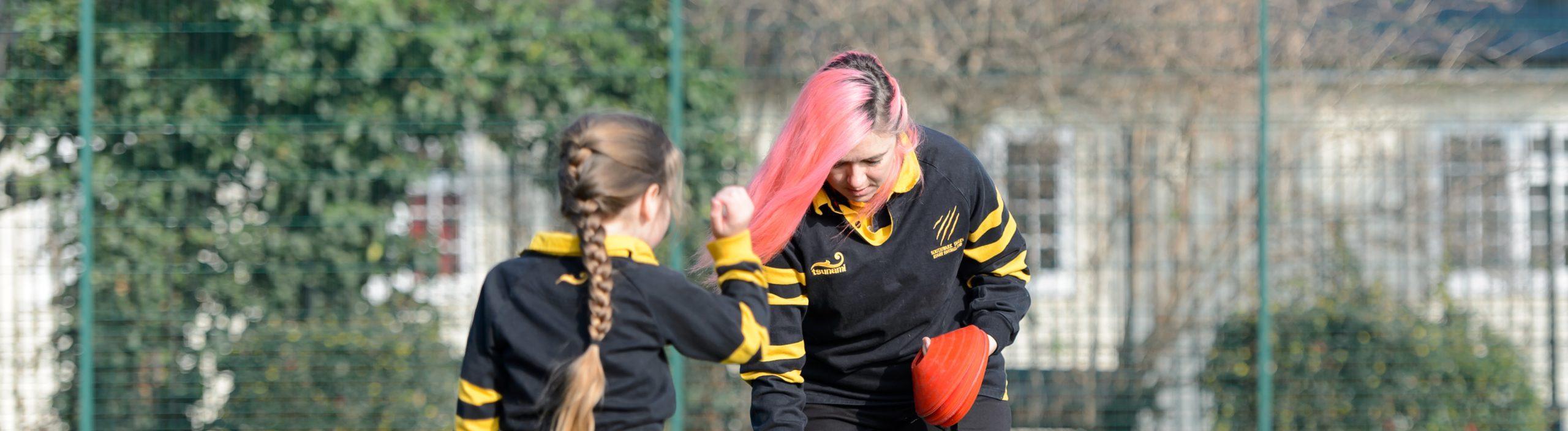 Female coach and young girl playing rugby